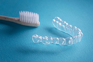 an Invisalign aligner next to a toothbrush