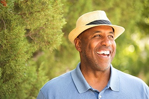 man in blue polo and fedora smiling with dental bridges in South Portland 