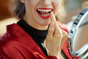 Woman holding mirror and pointing at tooth 
