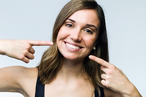 Woman with perfect teeth pointing at smile