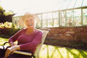 Man with implant dentures in South Portland, ME sitting on couch and smiling