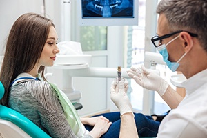 dentist showing his patient a dental implant