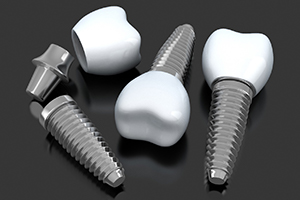 three dental implants with abutments and crowns lying on a flat surface