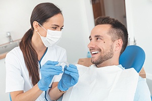 A dentist showing a male patient how to properly use Invisalign