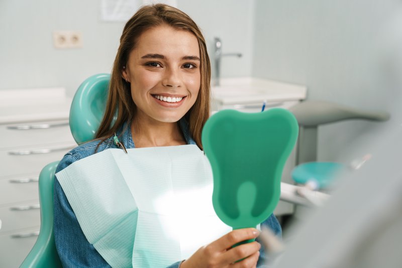 Woman cosmetic dentistry patient holding hand mirror 