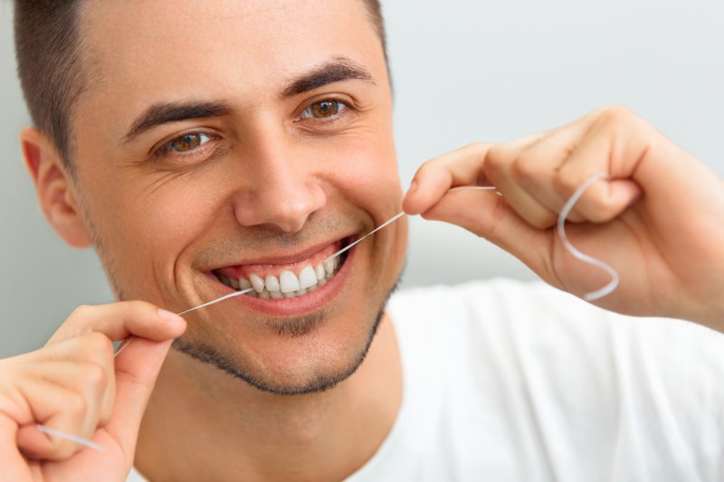 young man flossing teeth 