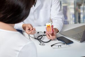 Dentist explaining to patient root canal therapy using model of infected tooth.